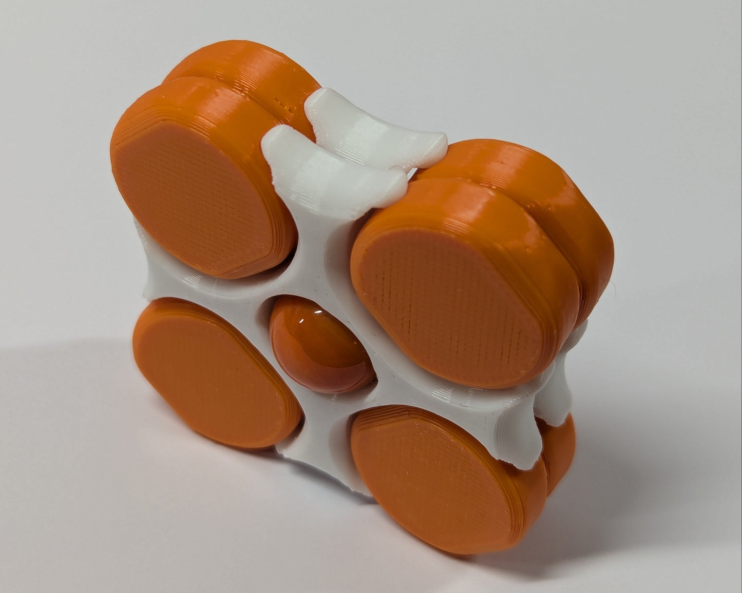 LodeStones fidget toy with white frames, orange magnet spinners and an orange marble
